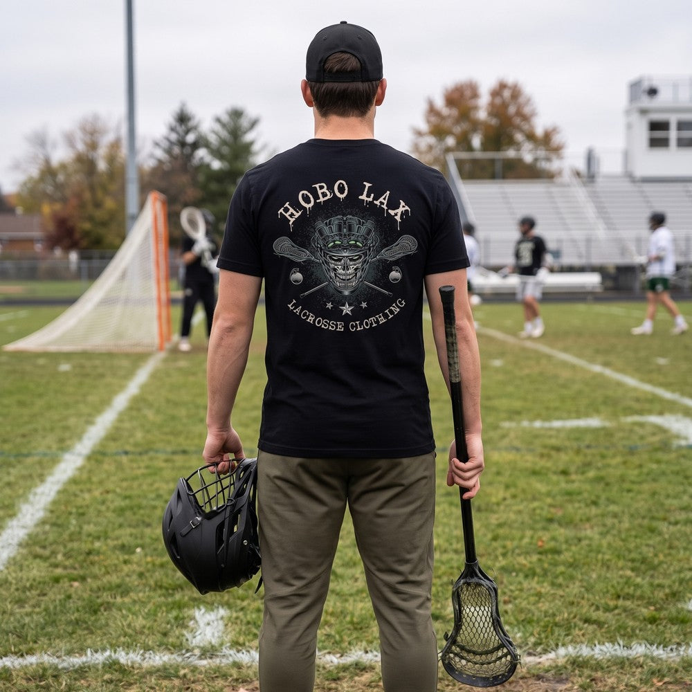 Man on a lacrosse sideline wearing the black Tactical Clear tee, back view of the Hobo Lax night-vision skull and crossed lacrosse sticks print