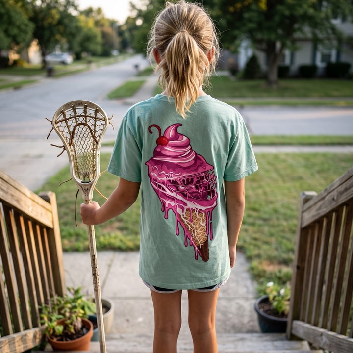 Youth Sideline Scoop Tee in seafoam worn by a girl on a front porch, back view showing the pink ice cream cone lacrosse helmet print