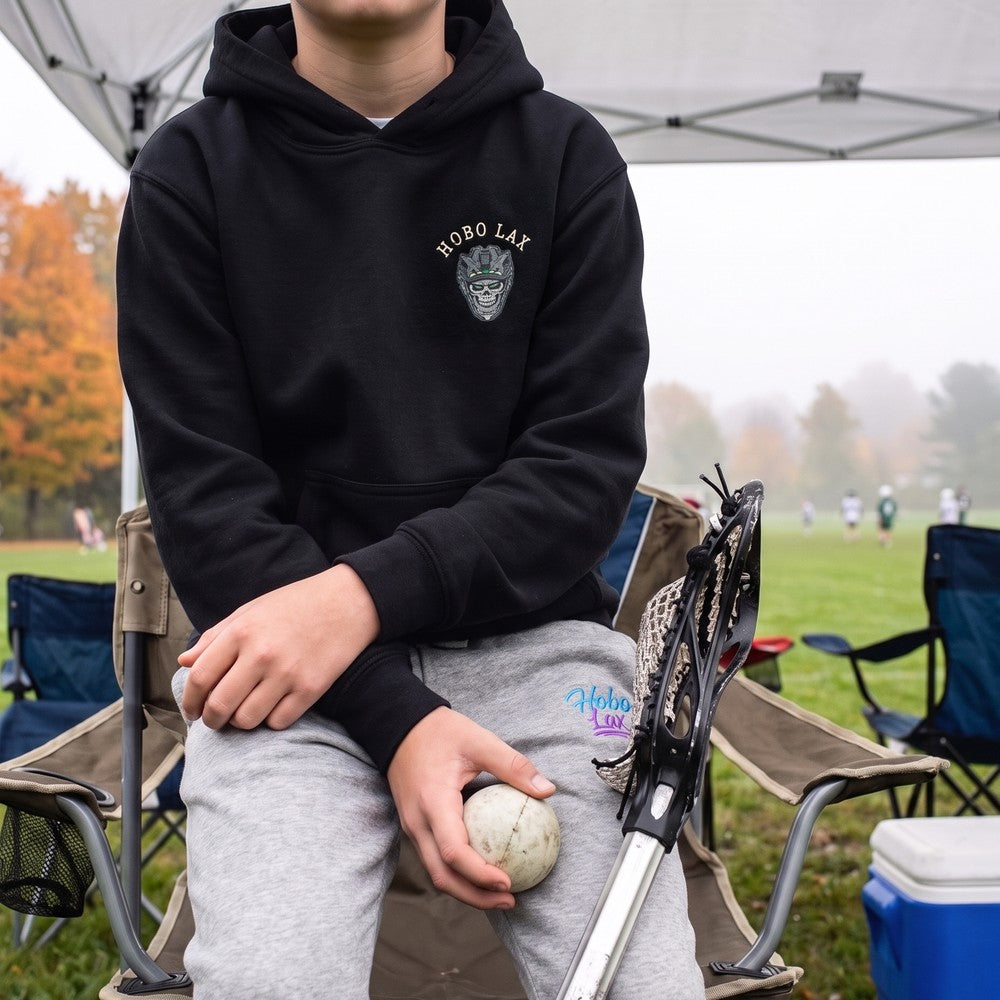 Youth lacrosse player in the black Youth Tactical Clear Hoodie and grey Hobo joggers, front view