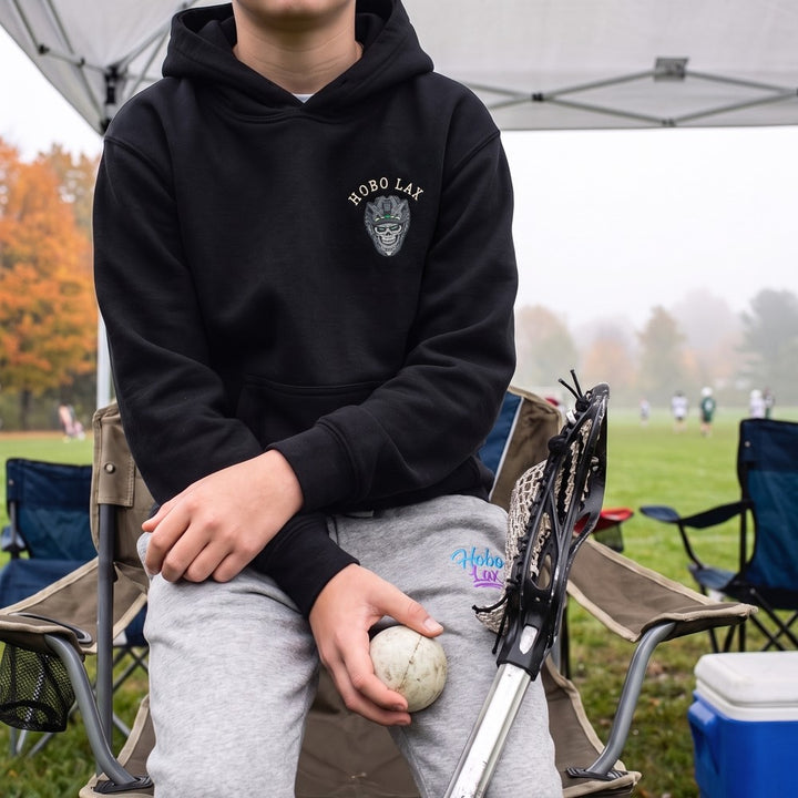 Youth lacrosse player in the black Youth Tactical Clear Hoodie and grey Hobo joggers, front view